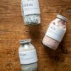 Three jars of bath salts laid on a wooden packground, dream, uplift and calm.
