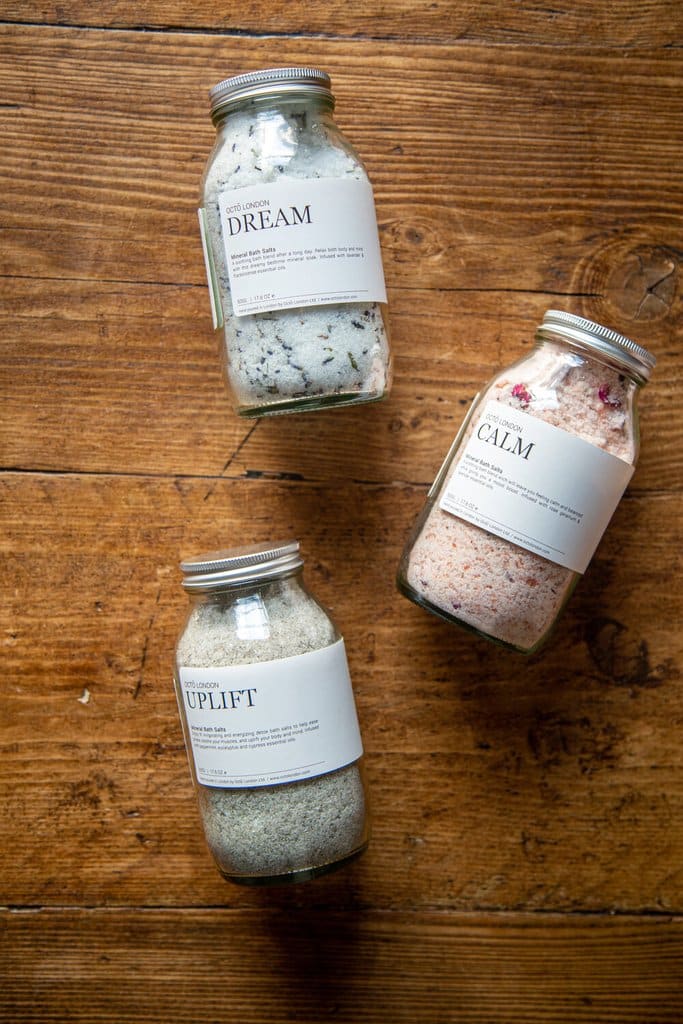 Three jars of bath salts laid on a wooden packground, dream, uplift and calm.